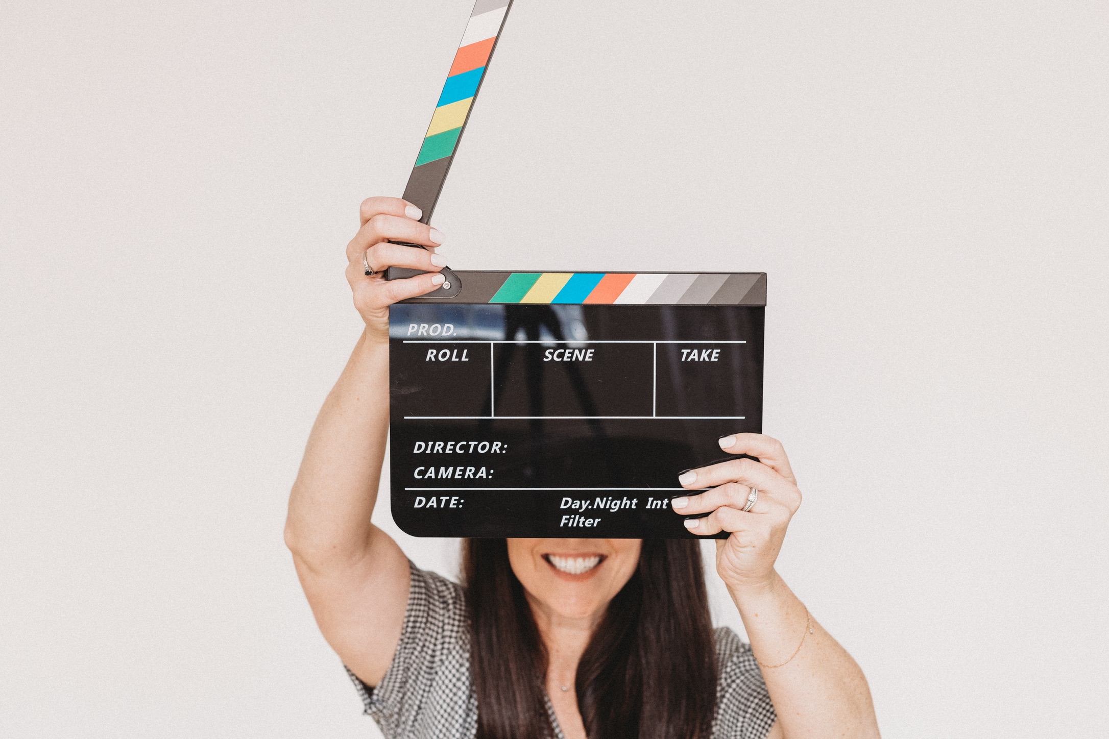 Kelli White, Indianapolis brand photographer, laughing behind a film clapperboard in her studio